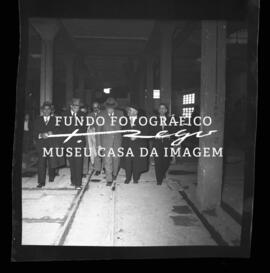 Grupo de pessoas em galpão fabril. Cooperativa dos Pedreiros, rua da Alegria.