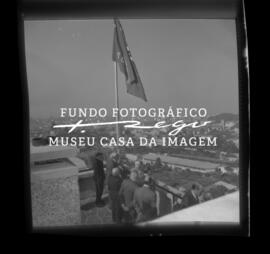 Grupo a estender bandeira da cooperativa com a cidade ao fundo. Cooperativa dos Pedreiros, rua da...